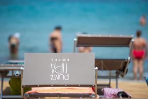 a sign on the beach with people in the background at Hotel Punta Tipa in Trapani