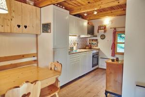 a kitchen with white cabinets and a wooden table at Srčna, Tri Vile, a beautiful log cabin with amazing view in Podčetrtek