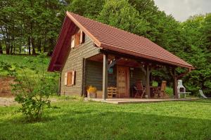 eine kleine Hütte mit einem Dach und einer Veranda in der Unterkunft Srčna, Tri Vile, a beautiful log cabin with amazing view in Podčetrtek