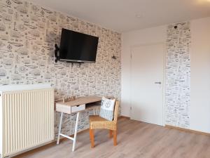 a room with a desk and a tv on a wall at Pension Blaue Nordseewelle in Neuharlingersiel