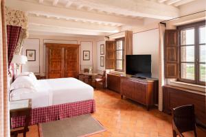 a hotel room with a large bed and a television at Castello Banfi - Il Borgo in Montalcino