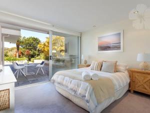 a bedroom with a bed and a balcony with a table at Bennetts by the Beach in Hawks Nest