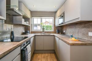 a kitchen with white cabinets and a sink and a window at Poets Corner in York