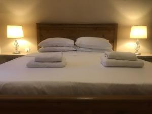 1 cama blanca grande con 4 almohadas y 2 lámparas en Sea view Apartments Portobello, en St Paul's Bay