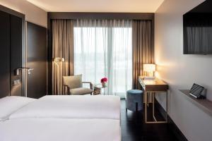 um quarto de hotel com uma cama, uma secretária e uma janela em AMANO East Side em Berlim