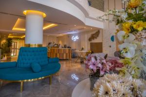 a blue couch in a lobby with flowers at The Address Palace Apartments in Dammam