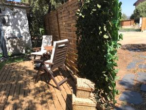 a wooden chair sitting on a patio next to a hedge at Cabaña en la naturaleza 2 in Madrid