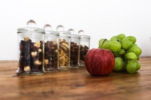 an apple and three jars of nuts and grapes on a table at Chambre d'hôtes A Vadina Porticcio in Porticcio