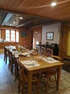 a large wooden table with chairs and a kitchen at Maison Le ROZET in Les Gras