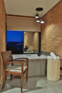 a bathroom with a tub and a chair and a window at DOM Hotel Boutique in Campos do Jordão