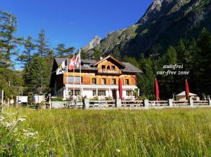 a large building with a fence in front of a mountain at Gasthaus Spinas in Bever