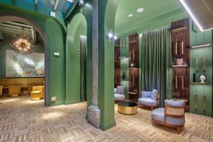 a waiting room with green walls and chairs and a chandelier at Hotel Number Nine in Florence