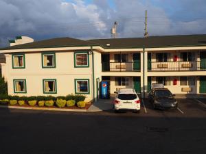 a large building with two cars parked in a parking lot at Garden State Inn in Absecon