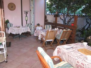 un restaurante con mesas, sillas y un árbol en Il Portico, en Uras