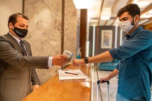 a man in a mask is handing a man a card at Sapphire Boutique Hotel in Thane