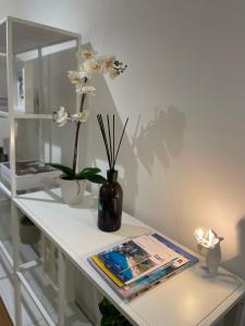 Vento Suites في كالياري: طاولة بيضاء مع مزهرية عليها زهور