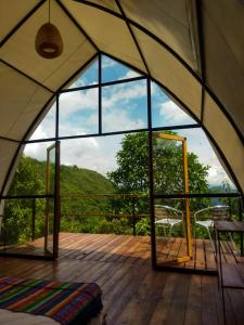 une chambre avec une grande fenêtre dans une tente dans l'établissement Ecoglamping Reserva Natural Paraíso Andino, à La Vega