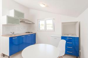 a white kitchen with blue cabinets and a white chair at Apartment SEA STAR in Hvar