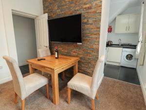 a dining room table with two chairs and a television on a brick wall at Flat 1 in Prestatyn