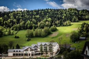 una casa en una colina con un campo verde en Hotel Olivia Medical SPA, en Skomielna Czarna