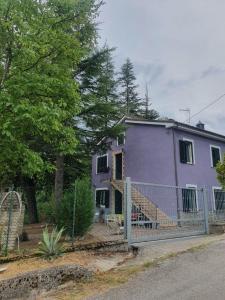 uma casa roxa com uma cerca em frente em Flamignano: un paradiso nel verde em Tossicia