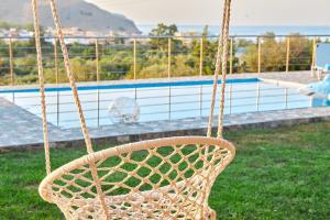 un columpio de ratán frente a una piscina en Villa Rose, en Georgioupolis