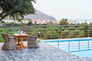 uma mesa e cadeiras ao lado de uma piscina em Villa Rose em Georgioupolis