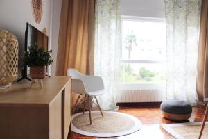 una sala de estar con una silla blanca frente a una ventana en Jovellanos Playa, en Ribadesella