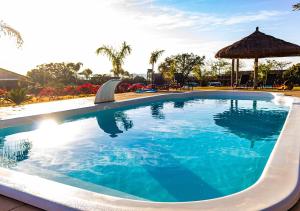 a large swimming pool with a umbrella in a resort at Rancho da Cachaça Pousada in Holambra