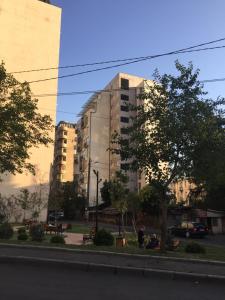 Un grand bâtiment avec des personnes assises devant lui dans l'établissement Holiday apartment, à Tbilissi