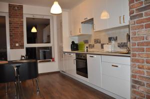a kitchen with white cabinets and a brick wall at Apartament Awiator Gdańsk in Gdańsk +8 photos