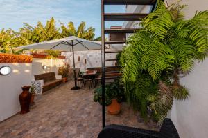 a patio with plants and an umbrella and a table at Casa Cucú in Puerto