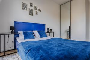 ein großes blaues Bett mit blauer Bettwäsche in einem Schlafzimmer in der Unterkunft Ilumino by LookAp in Łódź