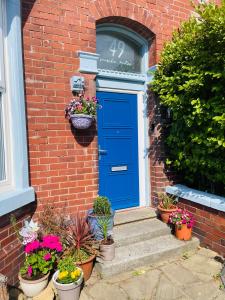 a blue door on a brick house with potted plants at Seaside Loft in Lytham St Annes