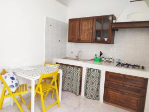 eine Küche mit einem Tisch und ein paar gelben Stühlen in der Unterkunft Al Meriggio Apartments in Brucoli