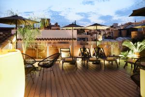 una terraza con sillas, mesas y sombrillas en un edificio en Elite Hotel - Gay Men Only, en Sitges