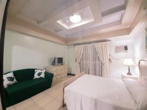 een slaapkamer met een wit bed en een groene bank bij Casa Micarosa Hotel in Manilla