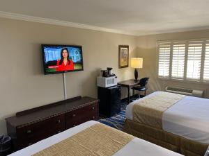 a hotel room with two beds and a flat screen tv at Travelodge by Wyndham Odessa in Odessa
