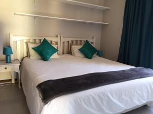 a bedroom with a white bed with green pillows at a Vue Guesthouse in Somerset West