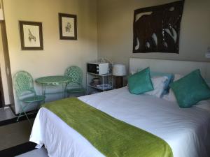 a bedroom with a large bed with green pillows at a Vue Guesthouse in Somerset West
