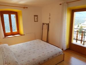 a bedroom with a bed and two windows at Appartamento Comelico Dolomiti in Candide