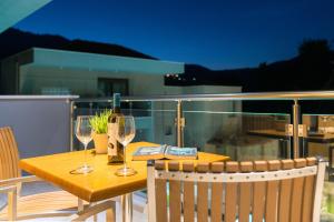 a wooden table with two wine glasses on a balcony at Mary's Luxury in Chrysi Ammoudia