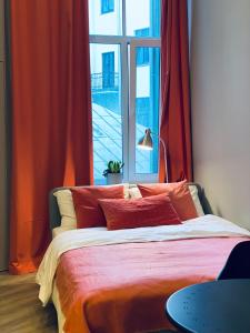 1 dormitorio con 1 cama con cortinas rojas y ventana en Flamingo apartment (FA), en Riga