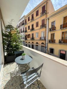 a small table and chairs on a balcony with buildings at Vento Suites in Cagliari