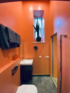 Un baño naranja con inodoro y lavabo. en Flamingo apartment (FA), en Riga