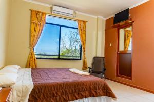 1 dormitorio con cama y ventana grande en Cucuve Eco Hostal, en Puerto Baquerizo Moreno