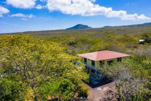 an aerial view of a house with a mountain in the background at Cucuve Eco Hostal in Puerto Baquerizo Moreno