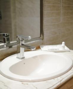 lavabo blanco en el baño con espejo en White Orchid, en Cox's Bazar