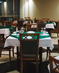 une salle à manger avec des tables recouvertes de nappes vertes et blanches dans l'établissement White Orchid, à Cox's Bazar