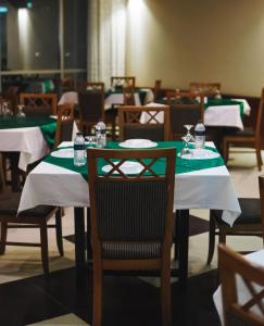 a dining room with tables with green and white tablecloths at White Orchid in Cox's Bazar
